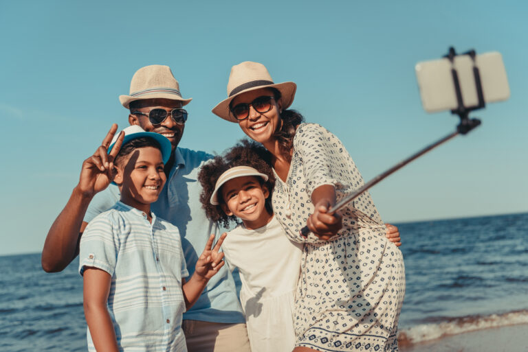 happy african american family taking selfie with smartphone on beach